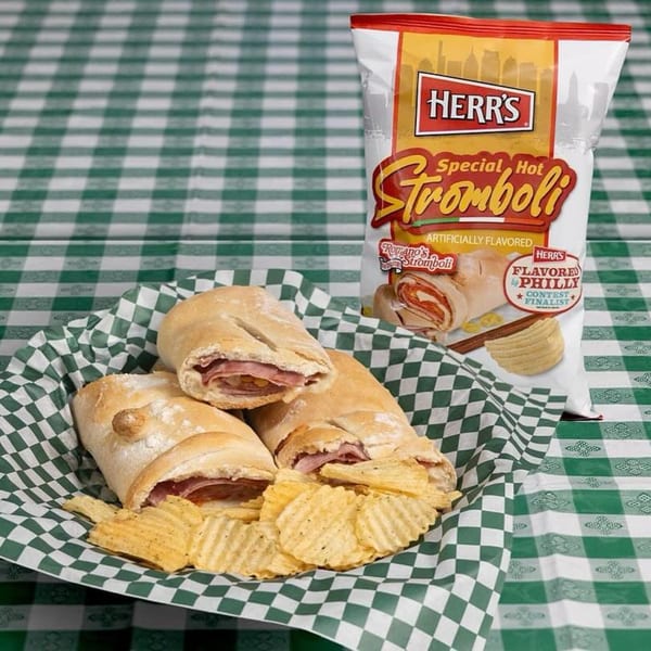 Three Romano's Pizzeria strombolis and Herr's potato chips in a basket on a green and white checkered tablecloth.
