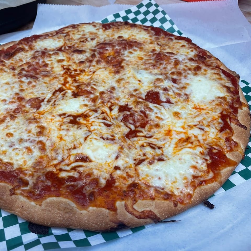 A whole Romano's Pizzeria cheese pizza with melted mozzarella and red sauce on checkered paper.